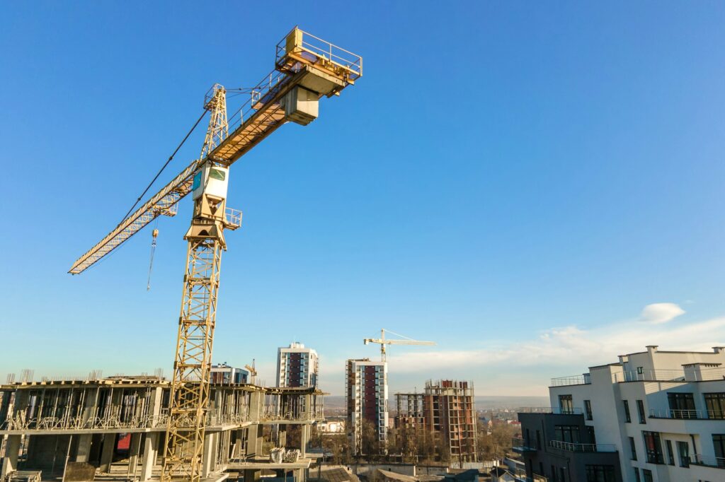 Aerial view of high tower crane and residential apartment buildings under construction. Real estate