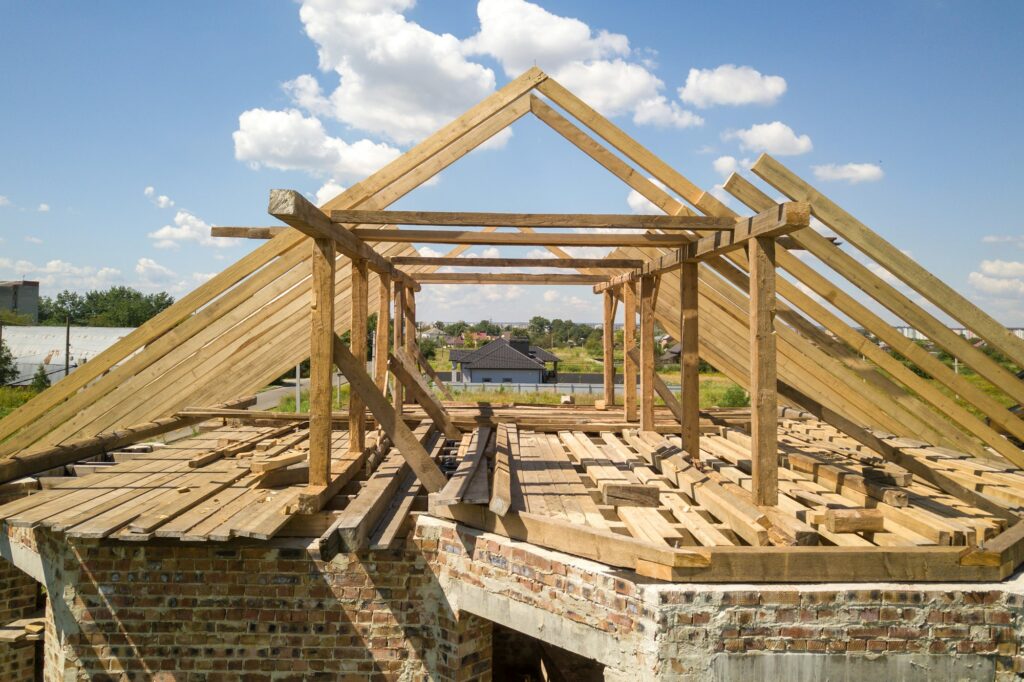 Aerial view of unfinished house with wooden roof frame structure under construction.