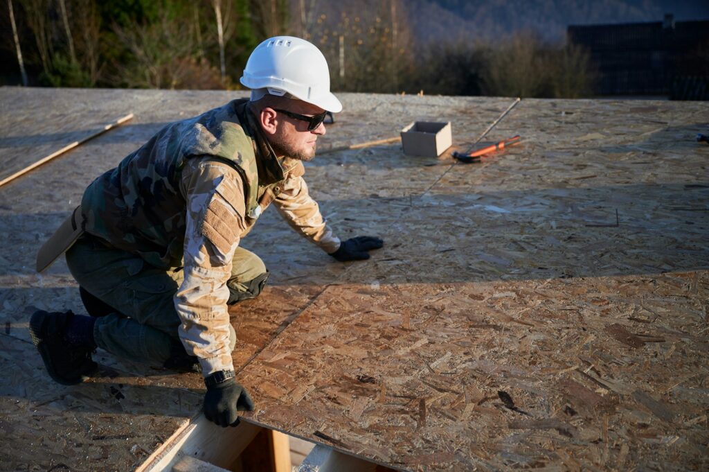 Man worker building wooden frame house, mounting wooden OSB board.