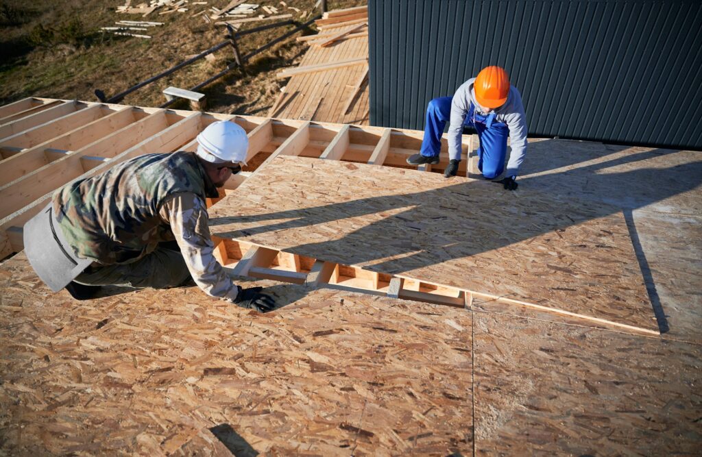 Man worker building wooden frame house, mounting wooden OSB board.